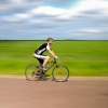 Cyclist riding past a green field
