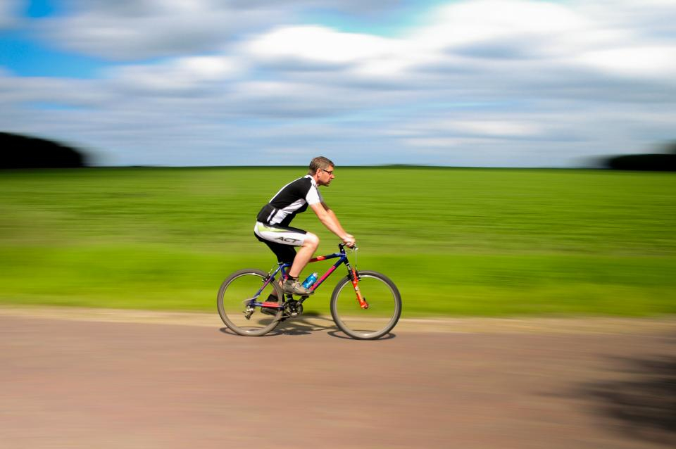 Cyclist riding past a green field