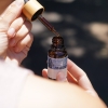Hand holding a dropper over a small bottle
