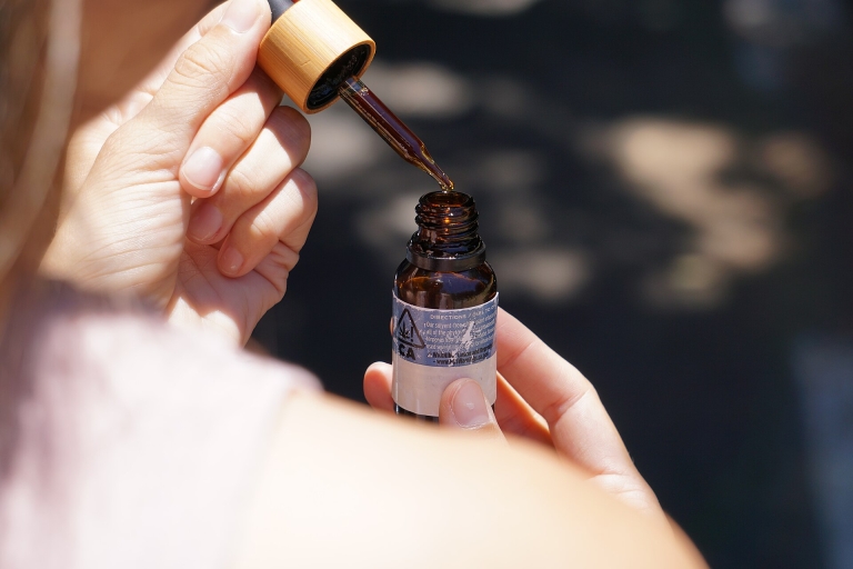 Hand holding a dropper over a small bottle