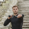 Athlete training with dumbbells outdoors
