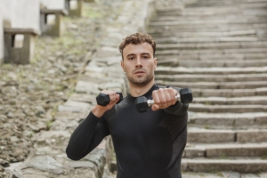 Athlete training with dumbbells outdoors