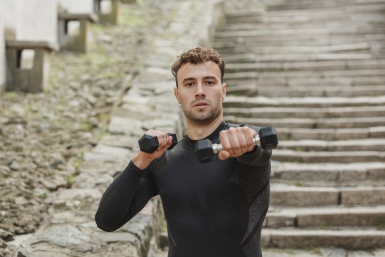 Athlete training with dumbbells outdoors