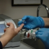 Gloved hands loading a sample into a lab analyzer