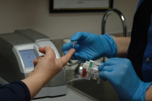 Gloved hands loading a sample into a lab analyzer