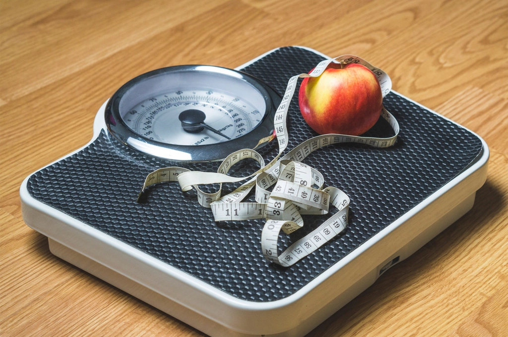 Bathroom scale with a measuring tape and apple