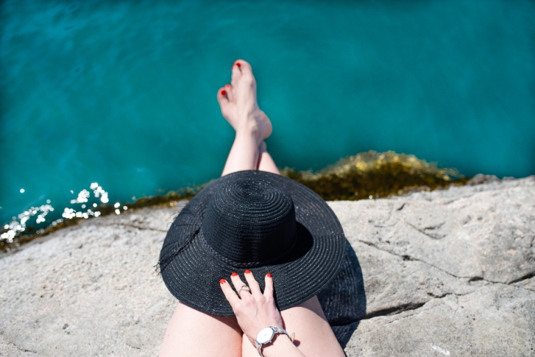 Person in a sun hat relaxing by the water