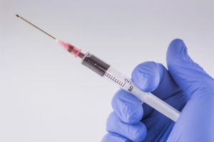 Gloved hand holding a syringe ready for an intramuscular injection